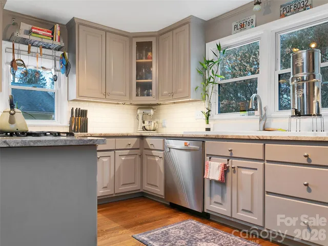a kitchen with stainless steel appliances granite countertop a sink and a stove next to a window