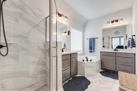 a spacious bathroom with a double vanity sink a mirror a bathtub and a shower