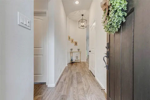 a view of a hallway with wooden floor and a chandelier