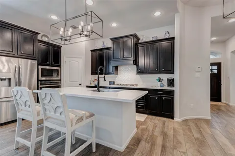 a kitchen with stainless steel appliances granite countertop a refrigerator oven a sink dishwasher and white cabinets with wooden floor