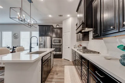 a kitchen with stainless steel appliances granite countertop a sink a stove and a refrigerator