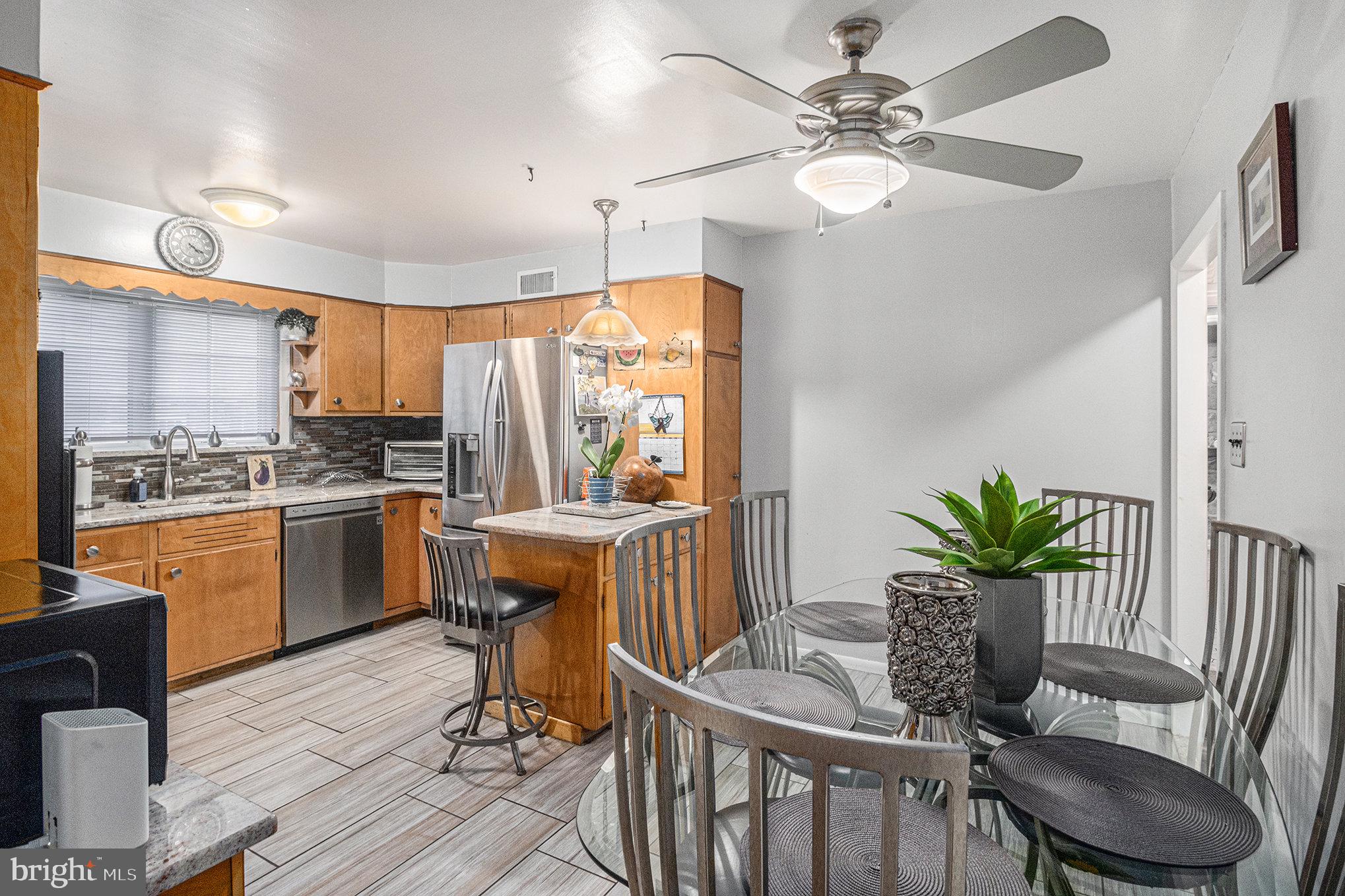 407 Rices Mill Road Wyncote, PA 19095 - Photo 7 of 29 a kitchen with stainless steel appliances a kitchen island hardwood floor sink stove dining table and chairs