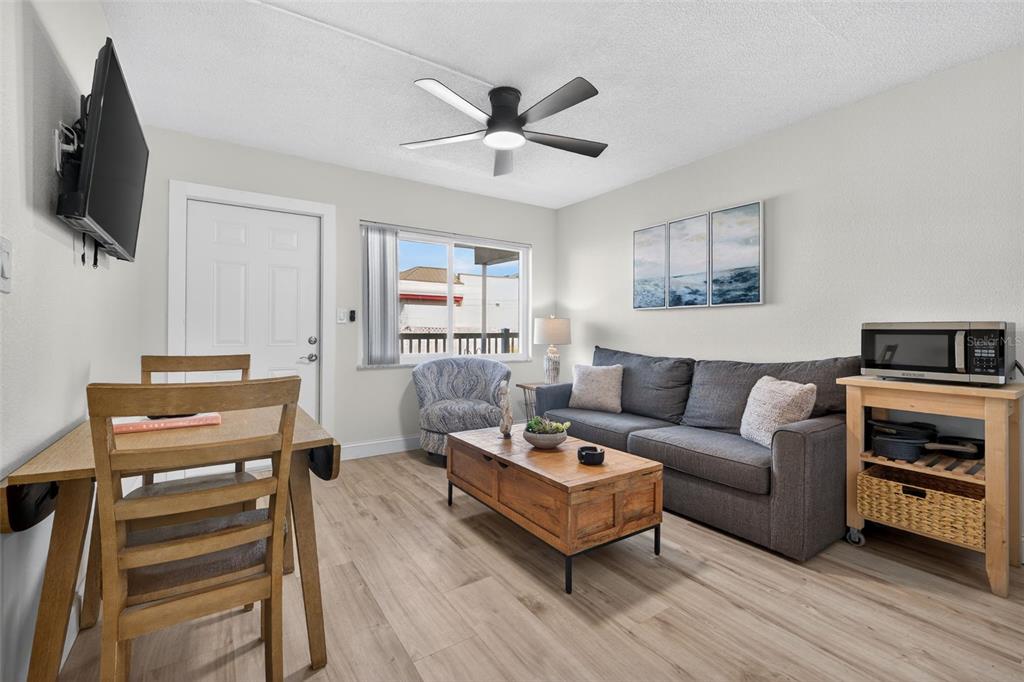 14251 Gulf Boulevard, Unit 5 Madeira Beach, FL 33708 - Photo 8 of 18 a living room with furniture a flat screen tv and a ceiling fan
