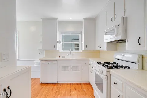 a kitchen with stainless steel appliances a sink cabinets and wooden floor