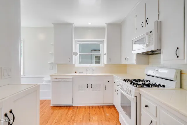 a kitchen with stainless steel appliances a sink cabinets and wooden floor