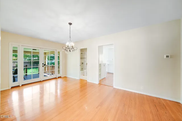 a view of an empty room with window and wooden floor