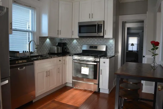 a kitchen with granite countertop a stove a microwave a sink and cabinets