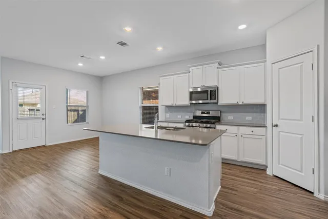 a kitchen with granite countertop white cabinets and black stainless steel appliances