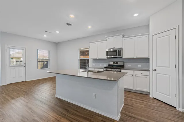 a kitchen with granite countertop white cabinets and black stainless steel appliances