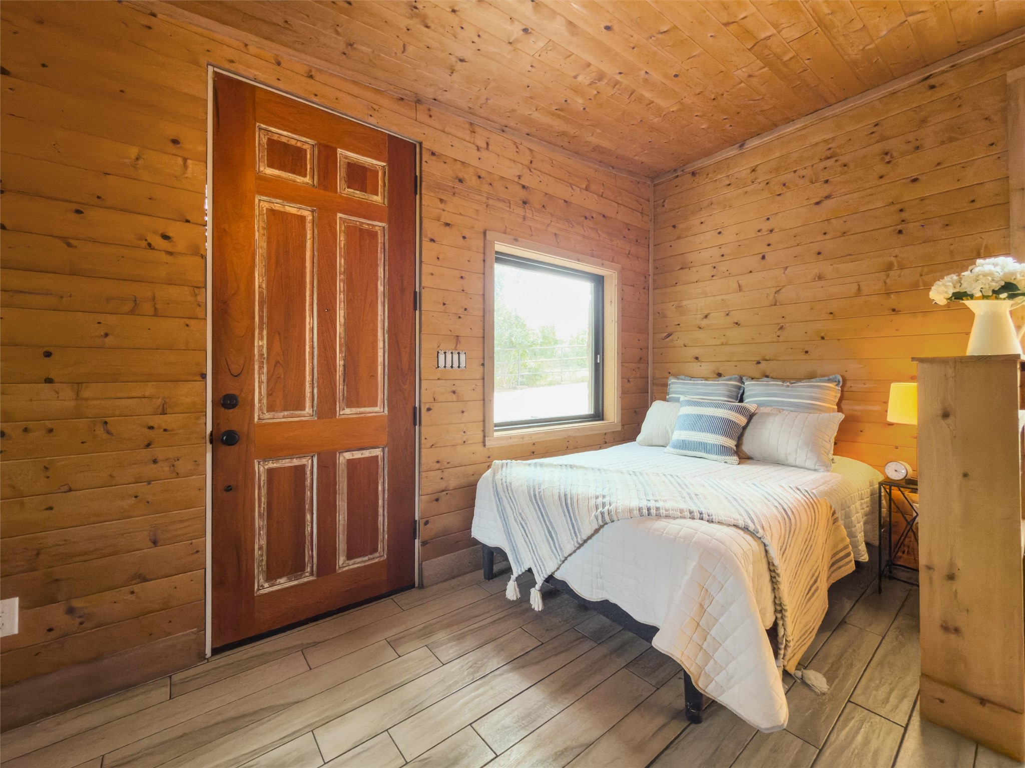 325 Eagle Rest Burnet, TX 78611 - Photo 19 of 40 Warm wood paneling envelops this inviting bedroom, featuring stylish plank flooring.