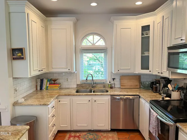 a kitchen with cabinets appliances a sink and a window