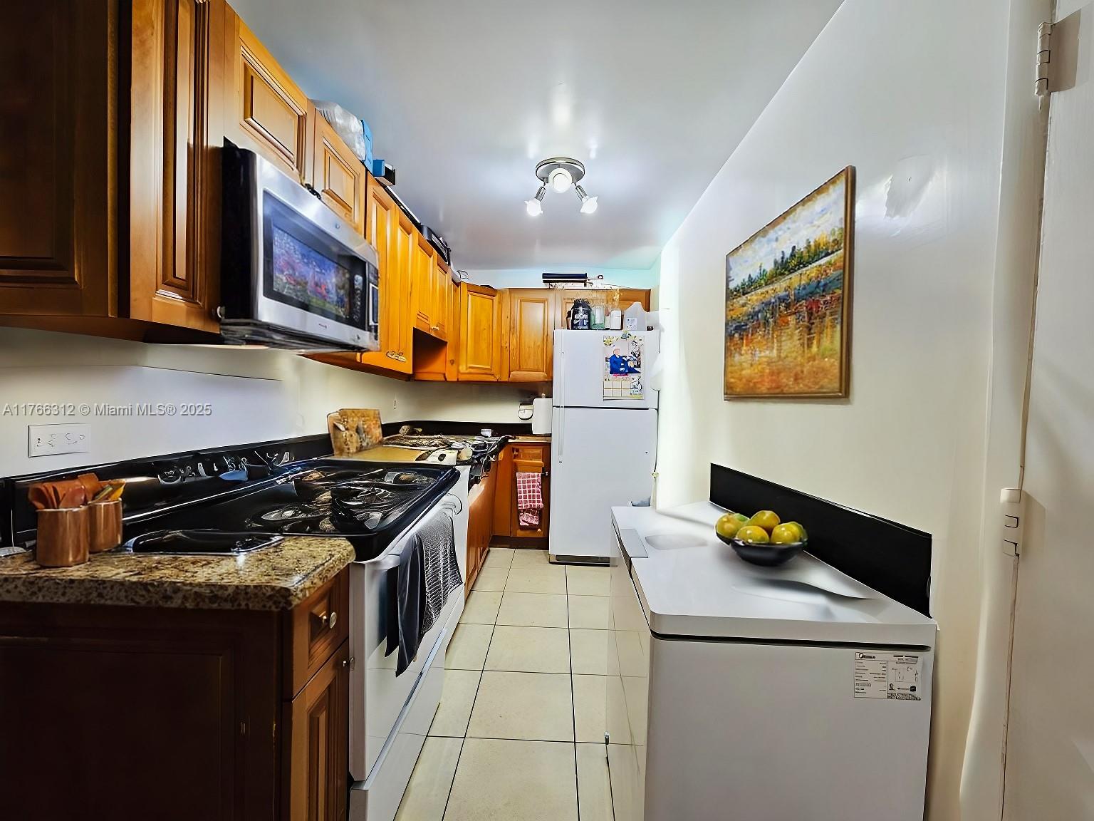 8788 Southwest 12th Street, Unit 103 Miami, FL 33174 - Photo 5 of 15 a kitchen with stainless steel appliances granite countertop a stove a sink and a microwave