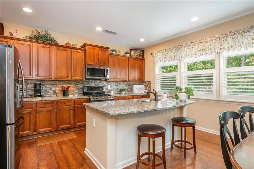 407 Ward Farm Drive Powder Springs, GA 30127 - Photo 21 of 67 a kitchen with stainless steel appliances granite countertop a stove top oven a sink dishwasher and a refrigerator with wooden floor