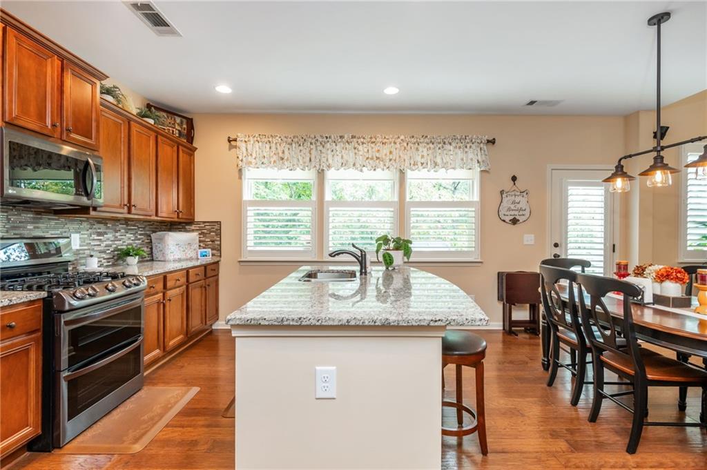 407 Ward Farm Drive Powder Springs, GA 30127 - Photo 23 of 67 a kitchen with stainless steel appliances granite countertop wooden floor a stove top oven a sink dishwasher a dining table and chairs with wooden floor