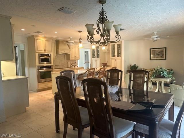 1261 Pine Ridge Road Naples, FL 34108 - Photo 8 of 13 Dining room featuring a chandelier, a textured ceiling, light tile patterned floors, and a ceiling fan