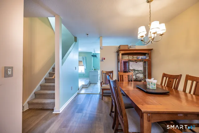 a dining room with wooden floor a chandelier a wooden table and chairs