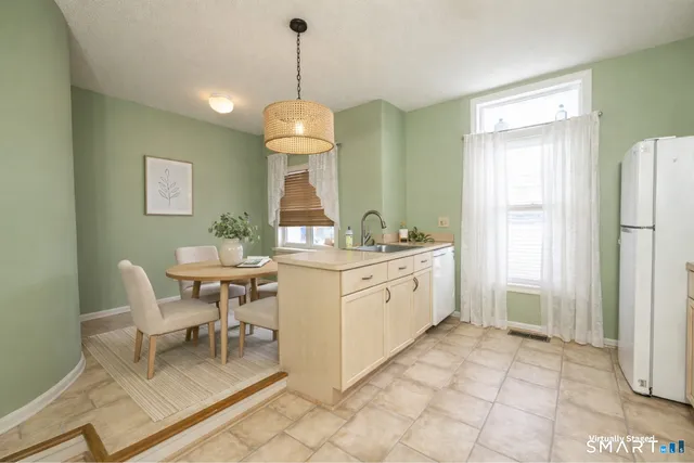a kitchen with stainless steel appliances kitchen island granite countertop a table chairs and a wooden floor