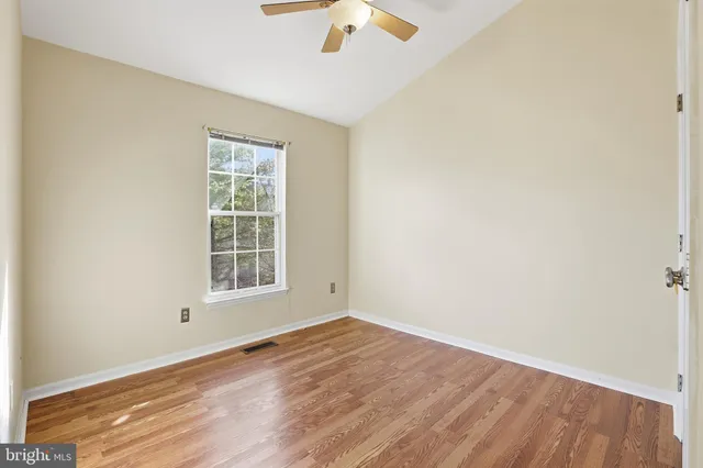 an empty room with wooden floor chandelier fan and window