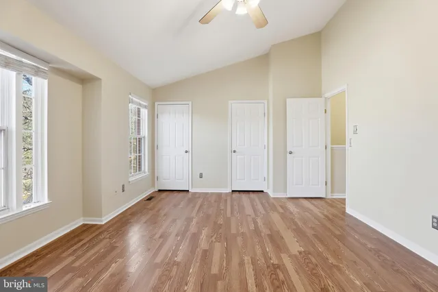 an empty room with wooden floor cabinet and windows