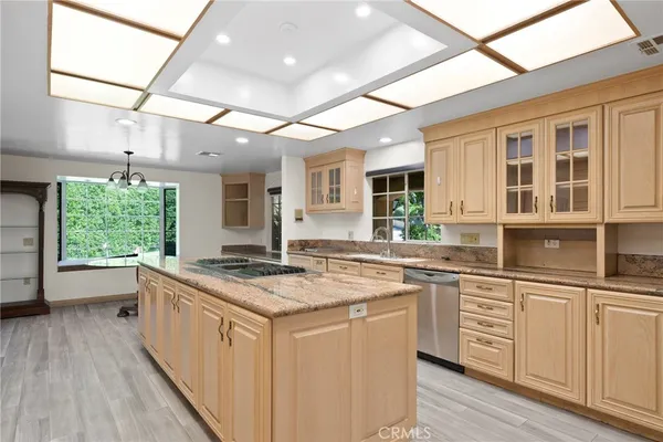 a kitchen with stainless steel appliances granite countertop a stove a sink dishwasher and white cabinets with wooden floor
