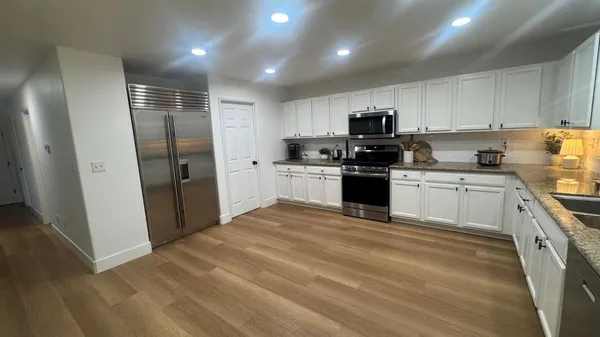 a kitchen with granite countertop a sink a counter top space stainless steel appliances and cabinets