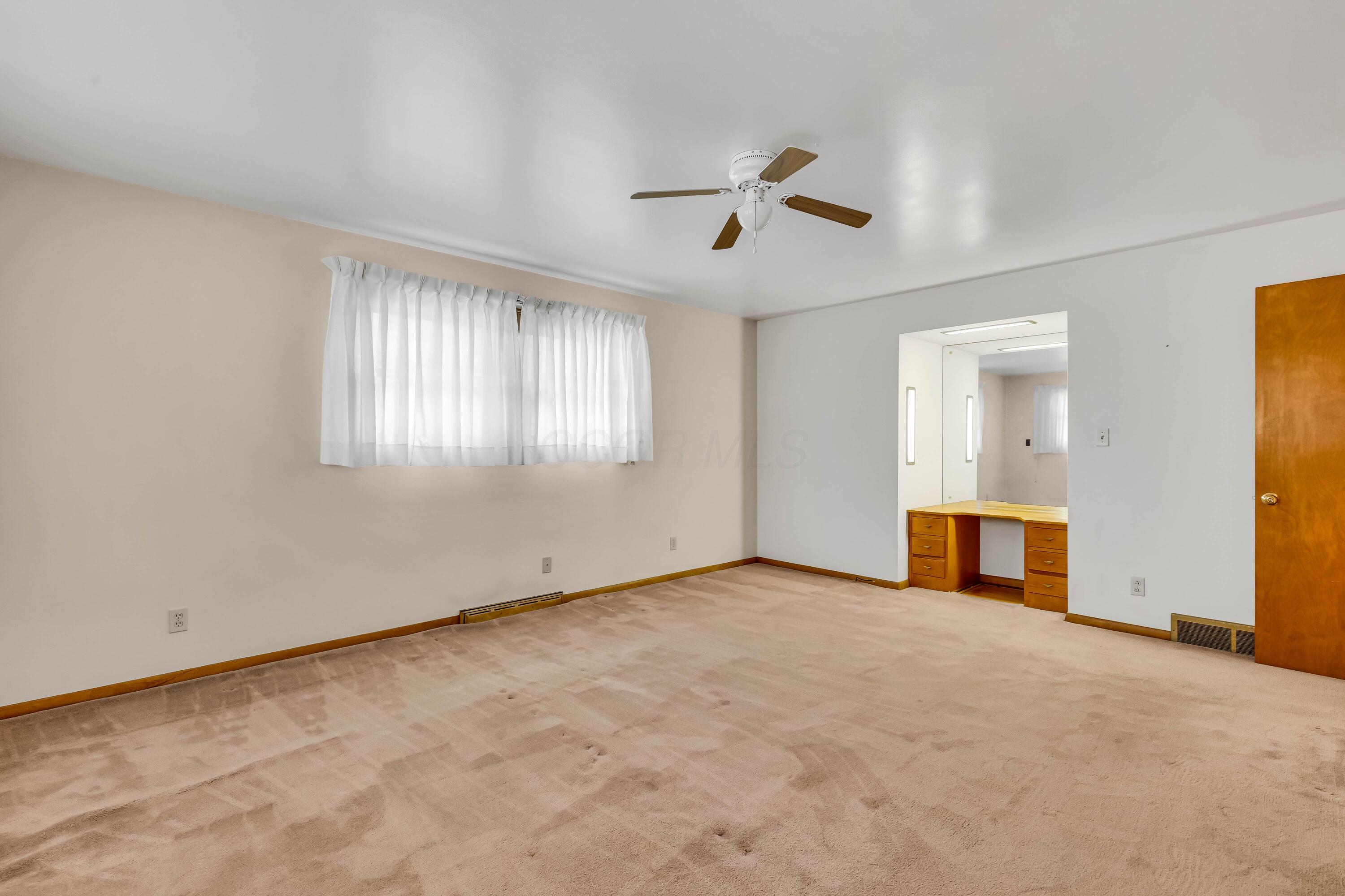1213 East Cooke Road Columbus, OH 43224 - Photo 34 of 57 • Tan carpet • Hardwood flooring under carpet • Tan painted walls • Lighted ceiling fan • Deep, lighted closet • Built-in desk/vanity