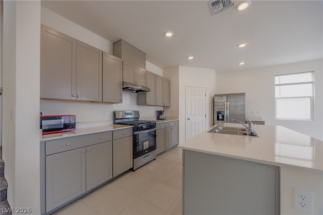 5927 Coja Street Las Vegas, NV 89113 - Photo 9 of 32 Kitchen featuring stainless steel appliances, gray cabinets, a sink, under cabinet range hood, and light countertops