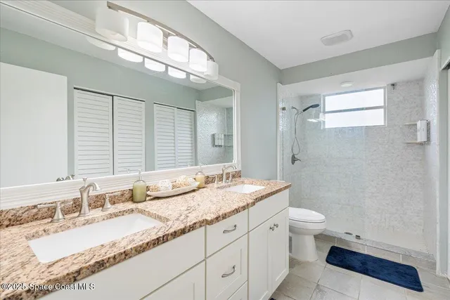 a bathroom with a granite countertop sink a toilet and shower
