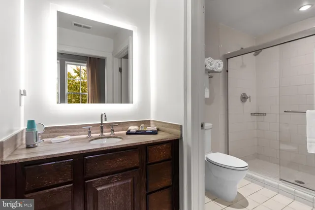 a bathroom with a granite countertop sink toilet a mirror a vanity and shower