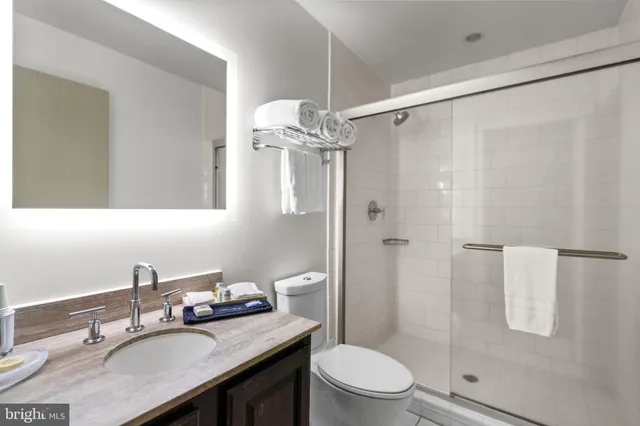 a bathroom with a granite countertop shower sink vanity mirror and toilet