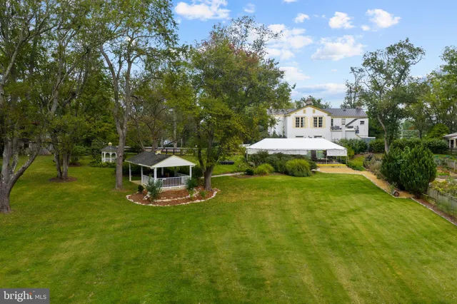 a white house with a big yard and large trees