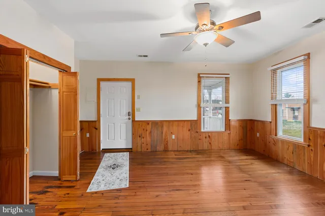 a view of empty room with wooden floor and fan