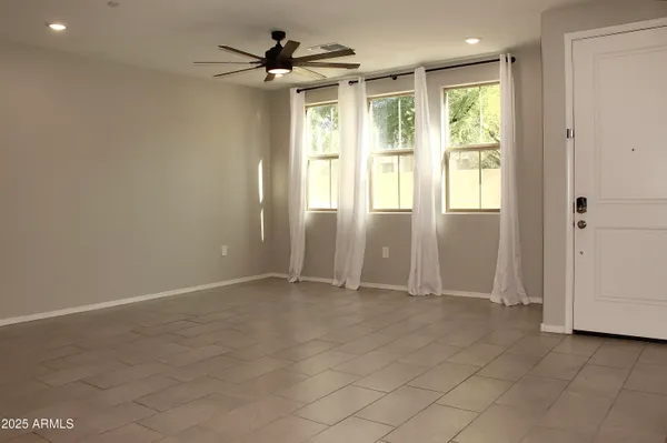 an empty room with windows and a ceiling fan