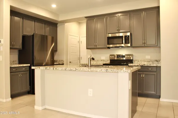a kitchen with stainless steel appliances granite countertop a refrigerator a stove a sink and a microwave