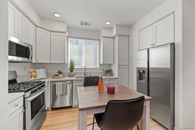 a kitchen with stainless steel appliances a stove a sink refrigerator and a refrigerator with wooden floor