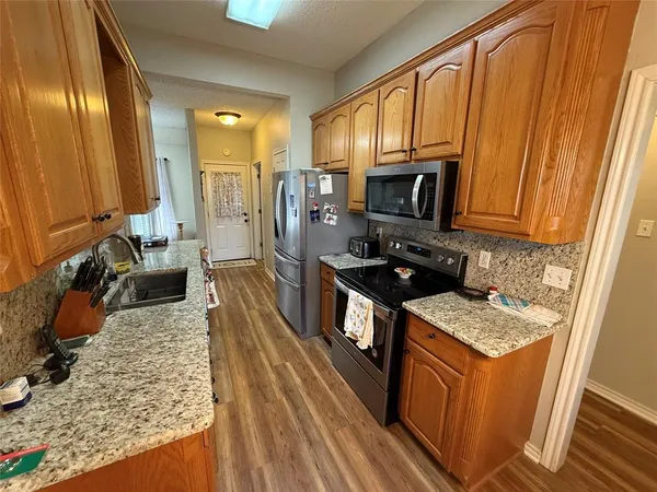 a kitchen with stainless steel appliances granite countertop a stove a sink dishwasher and a refrigerator