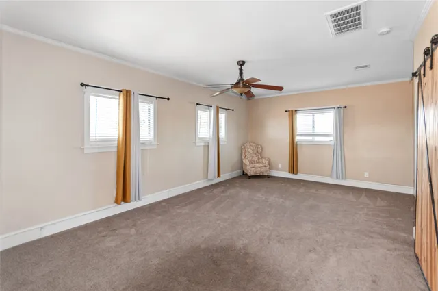 an empty room with windows and chandelier fan