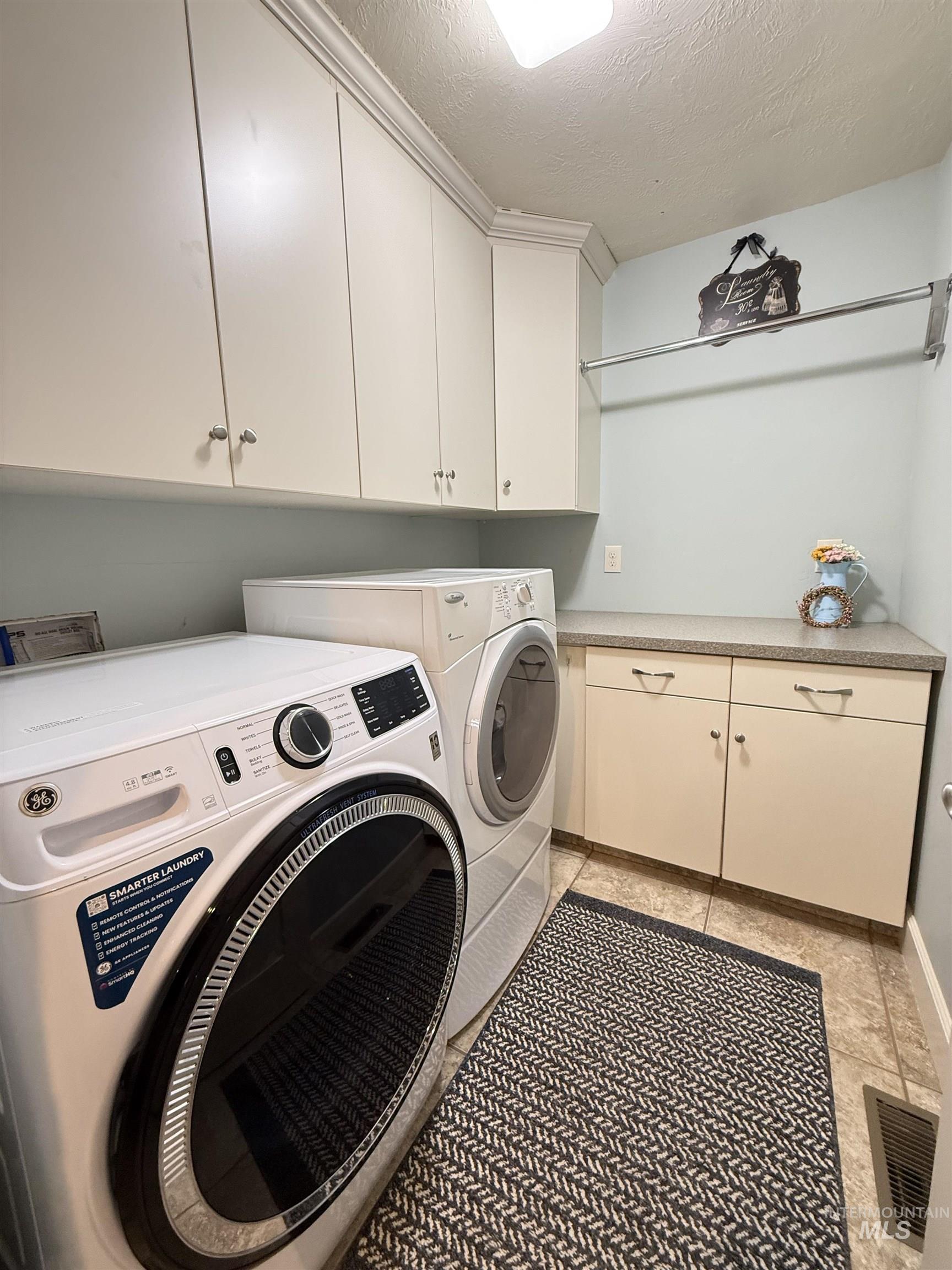 624 20th Street Rupert, ID 83350 - Photo 11 of 31 Laundry room with a textured ceiling, cabinet space, washer and clothes dryer, and light tile patterned flooring