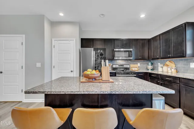 a kitchen with stainless steel appliances granite countertop a stove a sink a microwave a refrigerator and cabinets