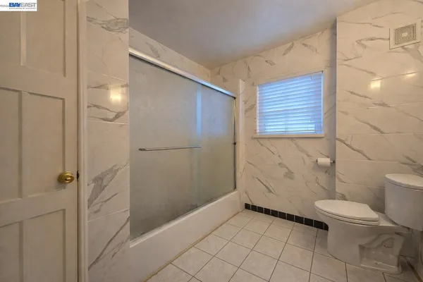 a bathroom with a granite countertop shower and a toilet