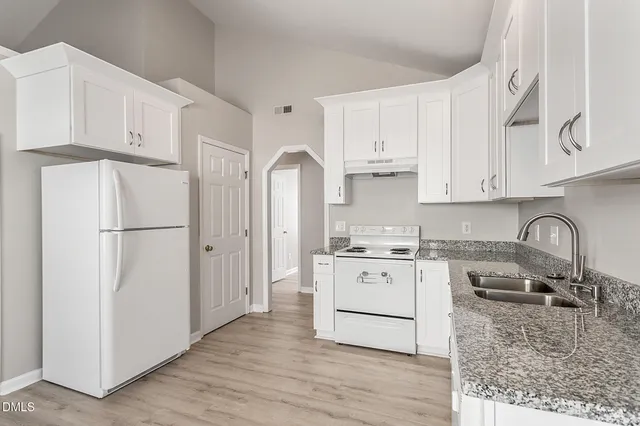 a kitchen with stainless steel appliances granite countertop a refrigerator sink and white cabinets