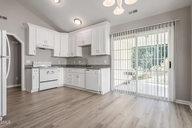 a kitchen with wooden floors white cabinets and stainless steel appliances