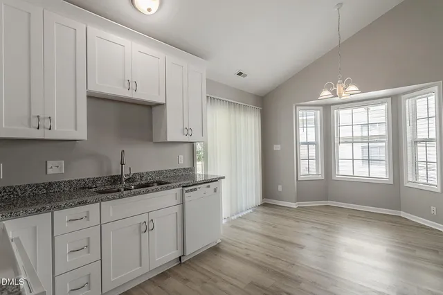 a kitchen with granite countertop white cabinets and a wooden floor
