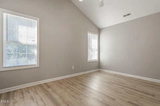 an empty room with wooden floor and windows