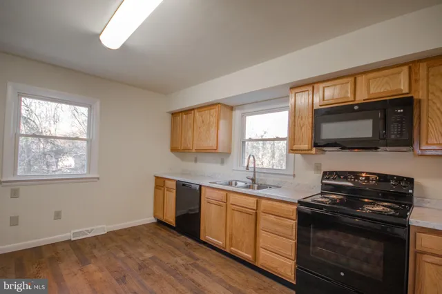 a kitchen with stainless steel appliances a stove sink microwave and window