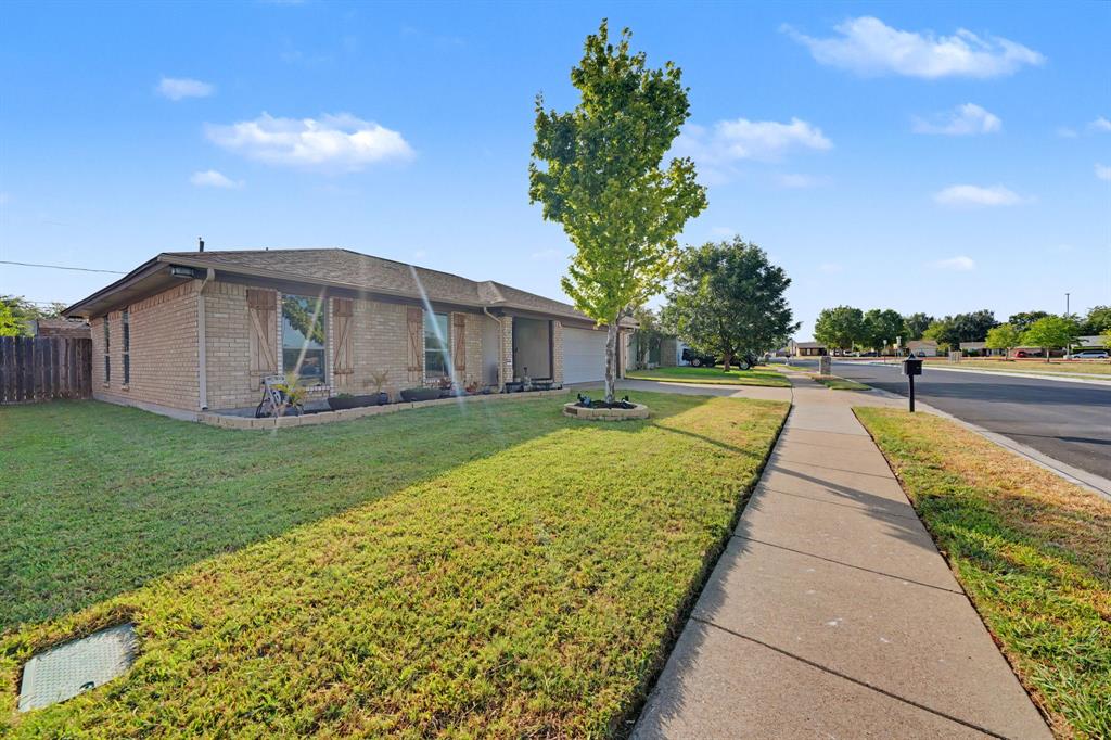7624 Maple Hill Road Watauga, TX 76148 - Photo 4 of 20 Brick exterior with a dark-shingle roof, wood shutters, and an attached garage