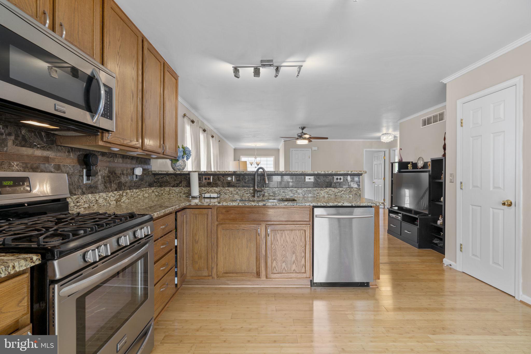 8057 Mayer Avenue Pasadena, MD 21122 - Photo 8 of 26 a kitchen with stainless steel appliances granite countertop a stove top oven a sink dishwasher a refrigerator and white cabinets with wooden floor