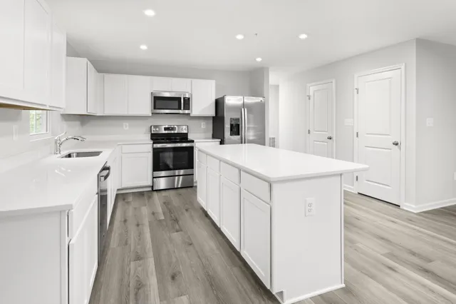 a kitchen with stainless steel appliances kitchen island wooden floors and white cabinets