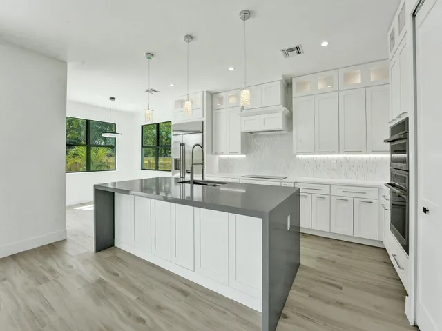 a large kitchen with stainless steel appliances granite countertop a lot of counter space and wooden floor