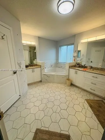 a large white kitchen with a sink a window and stainless steel appliances